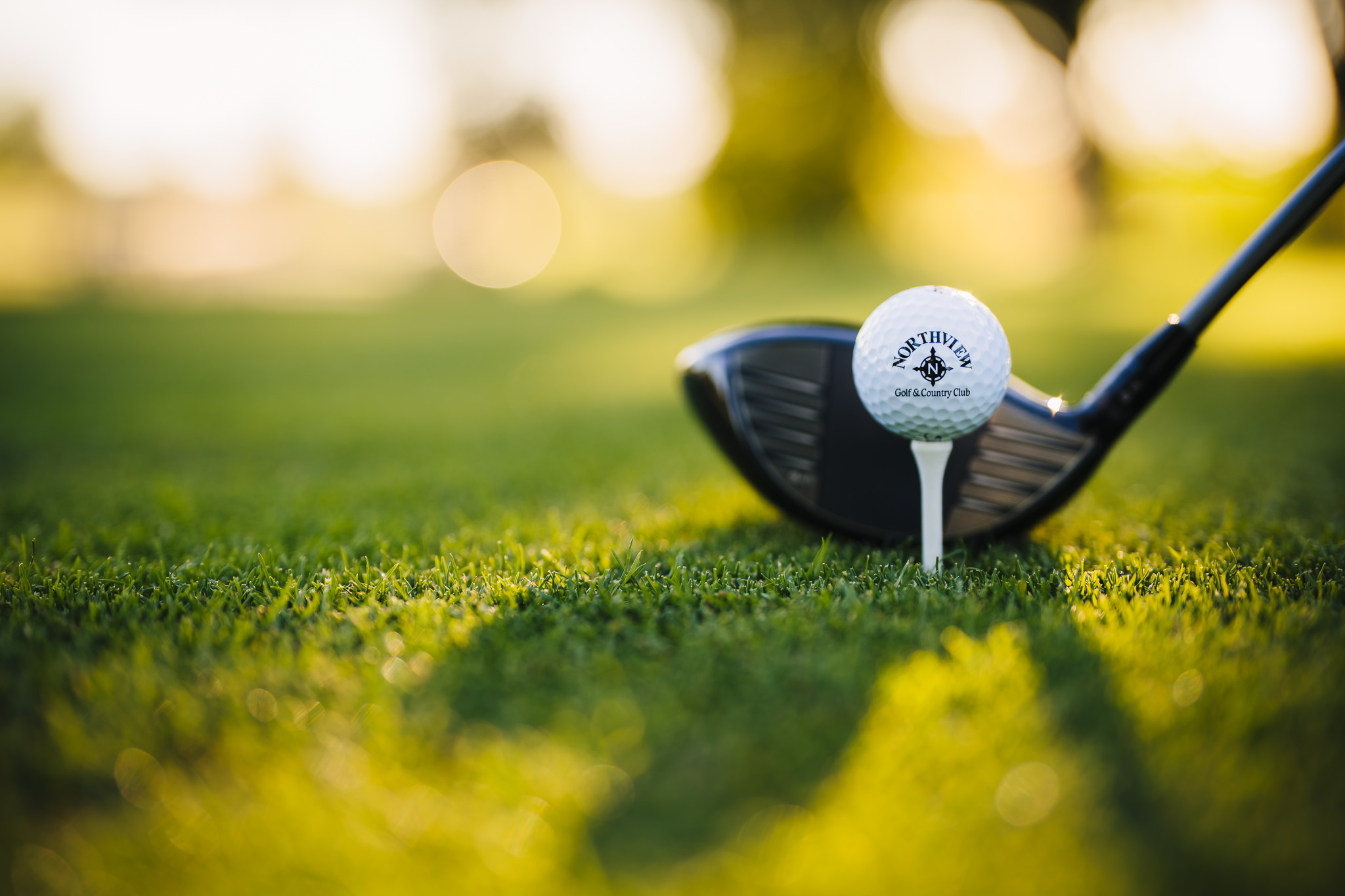 Close up view of a driver golf club and a Northview Golf branded golf ball