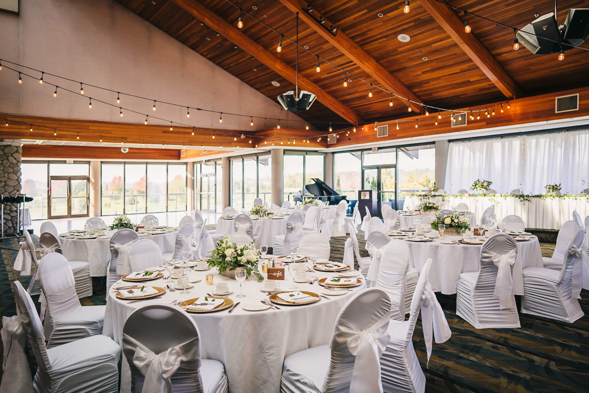 View inside the banquet hall with tables and chairs decorated in white