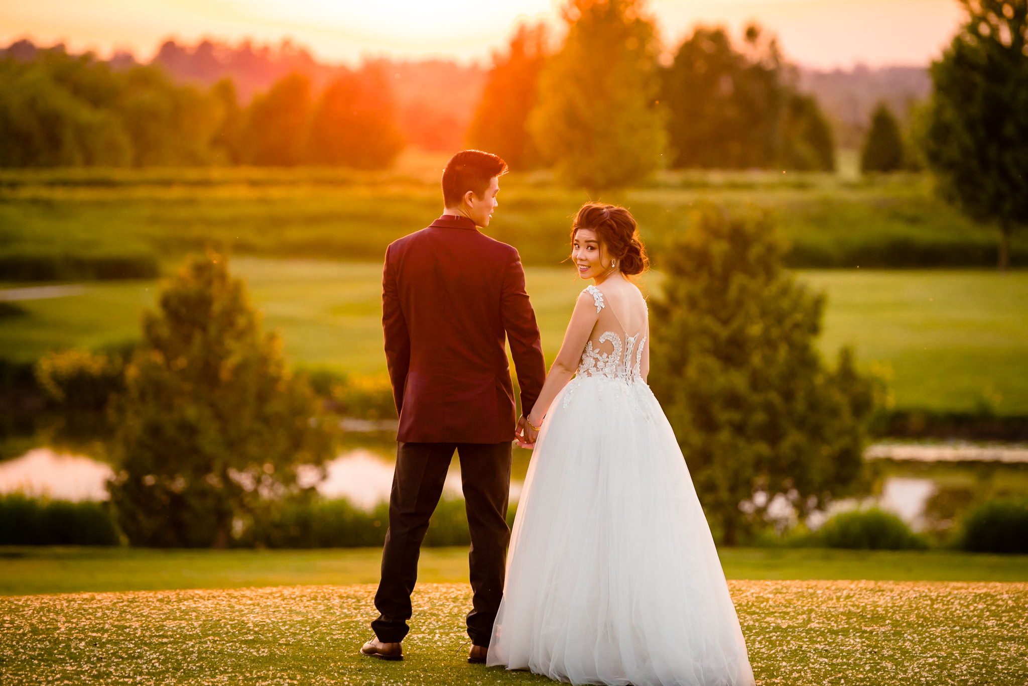 Bride and groom holding hands, while the bride smiles at the camera