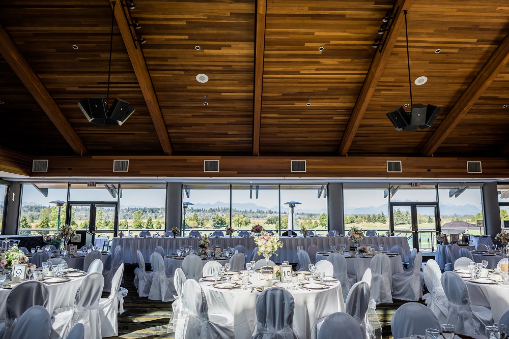 View inside the banquet hall of set tables and chairs decorated in white