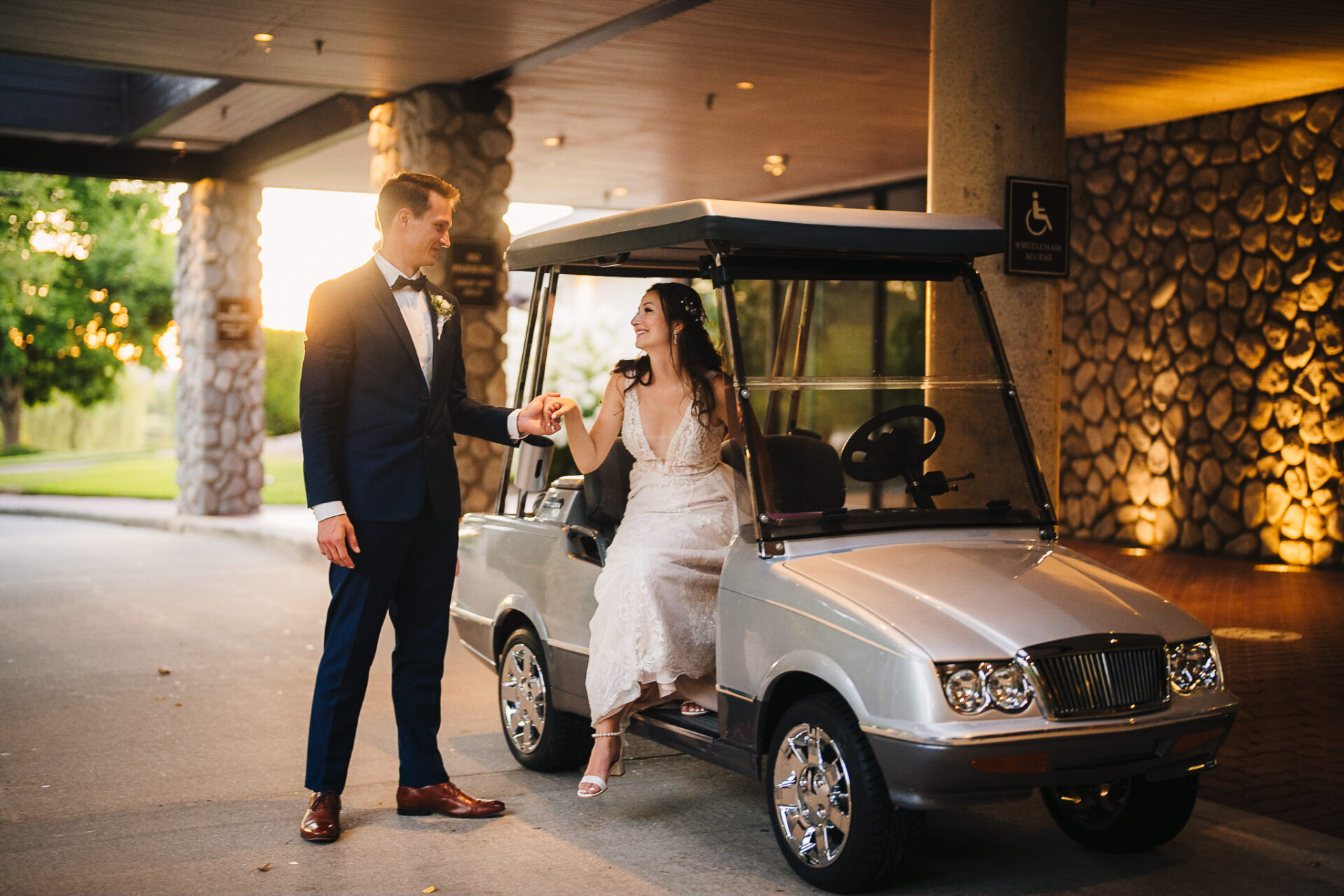 Groom offering his hand to the bride as she walks out of a golf cart