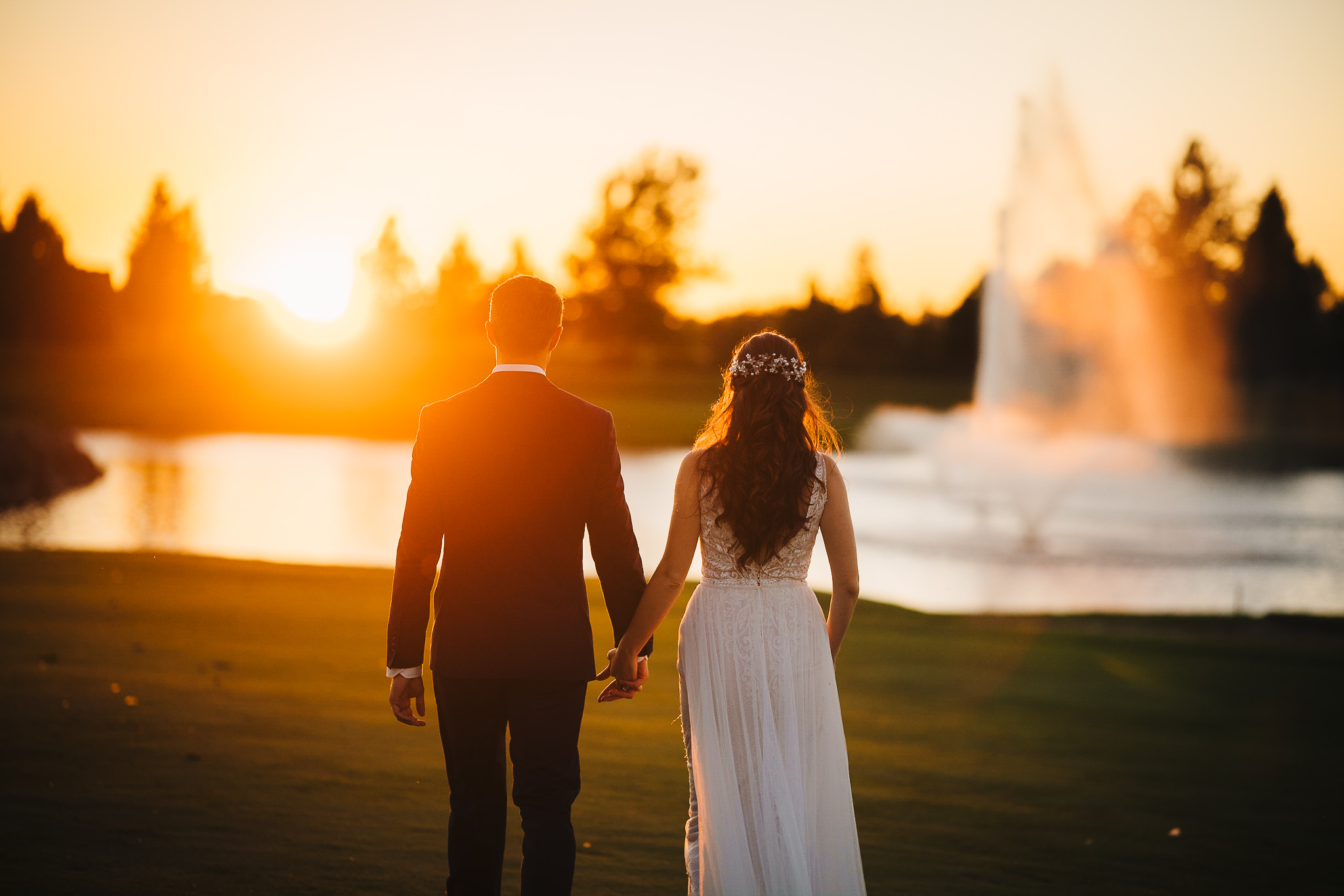 Bride and groom holding hands and walking into the sunset