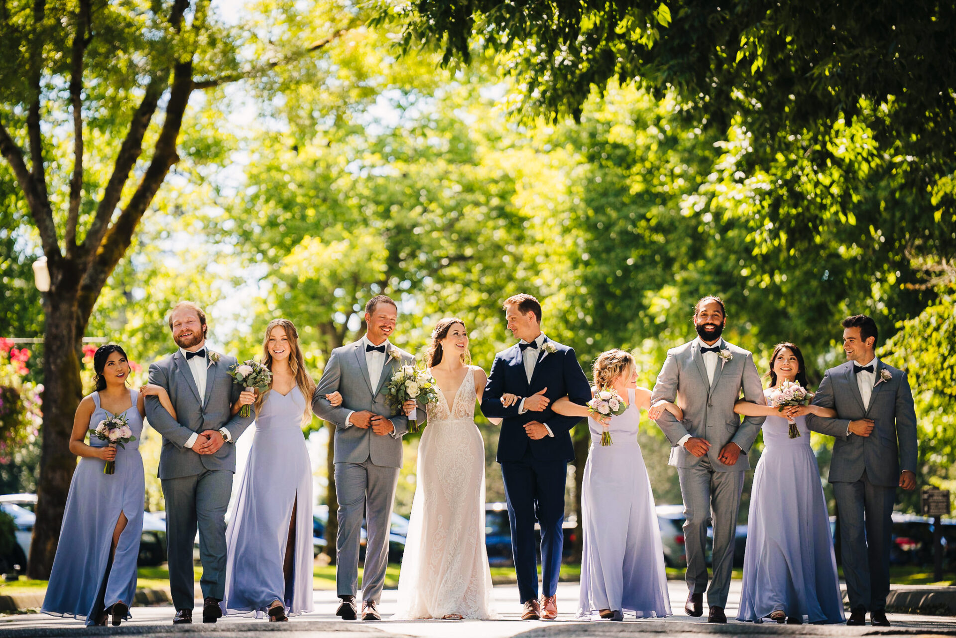 Wedding party locking arms and happily walking together