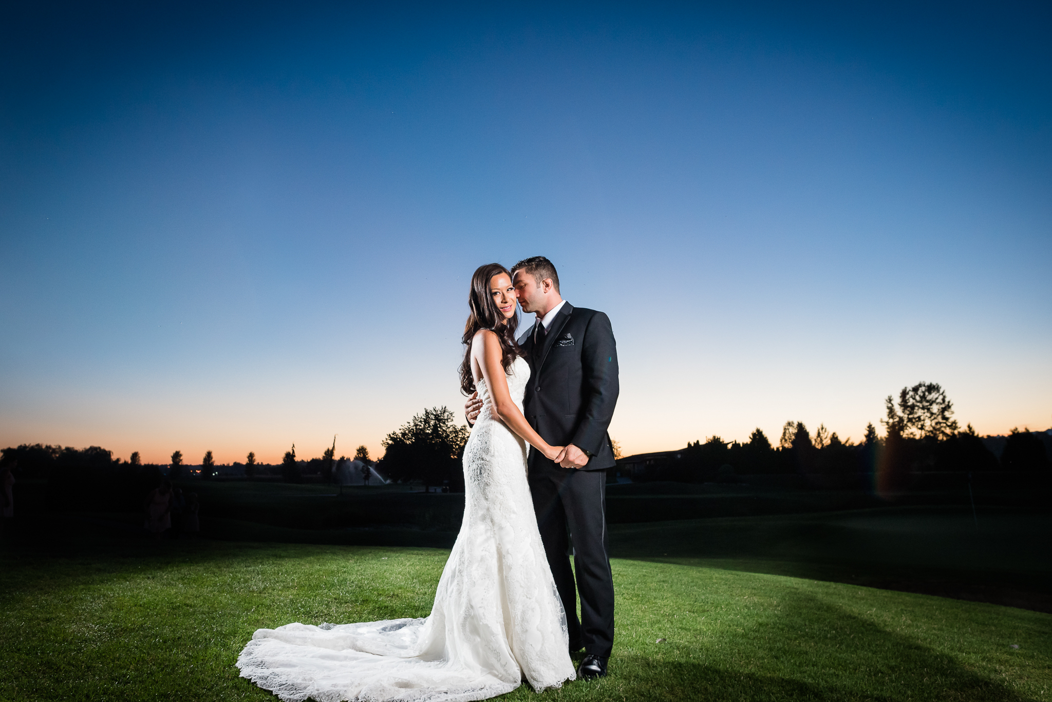 Bride andf groom posing for a photo, with the bride looking at the camera