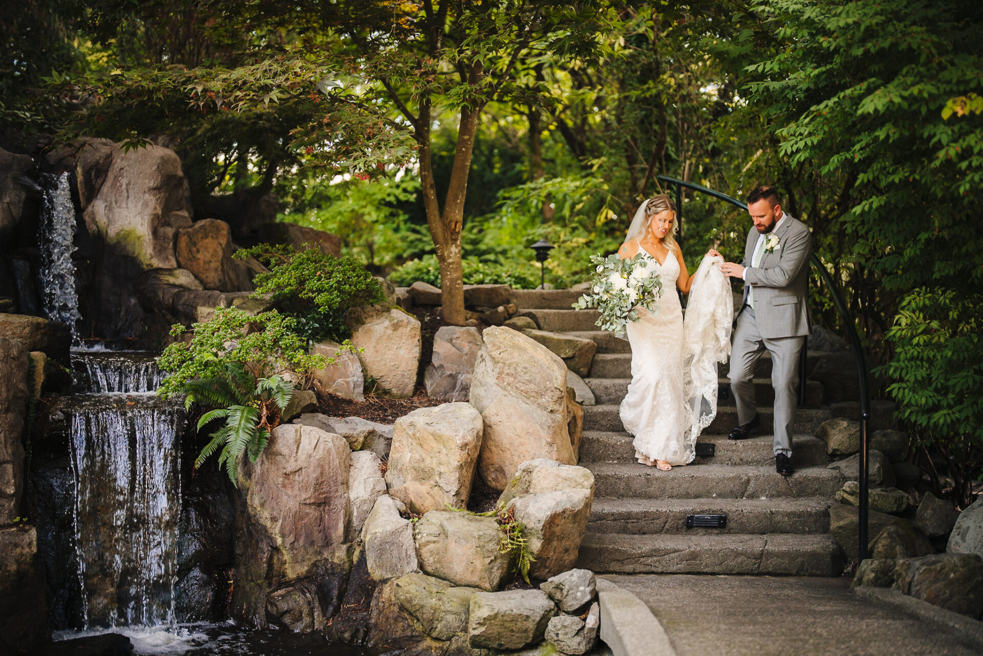 Groom helping bride walk down a set of stairs
