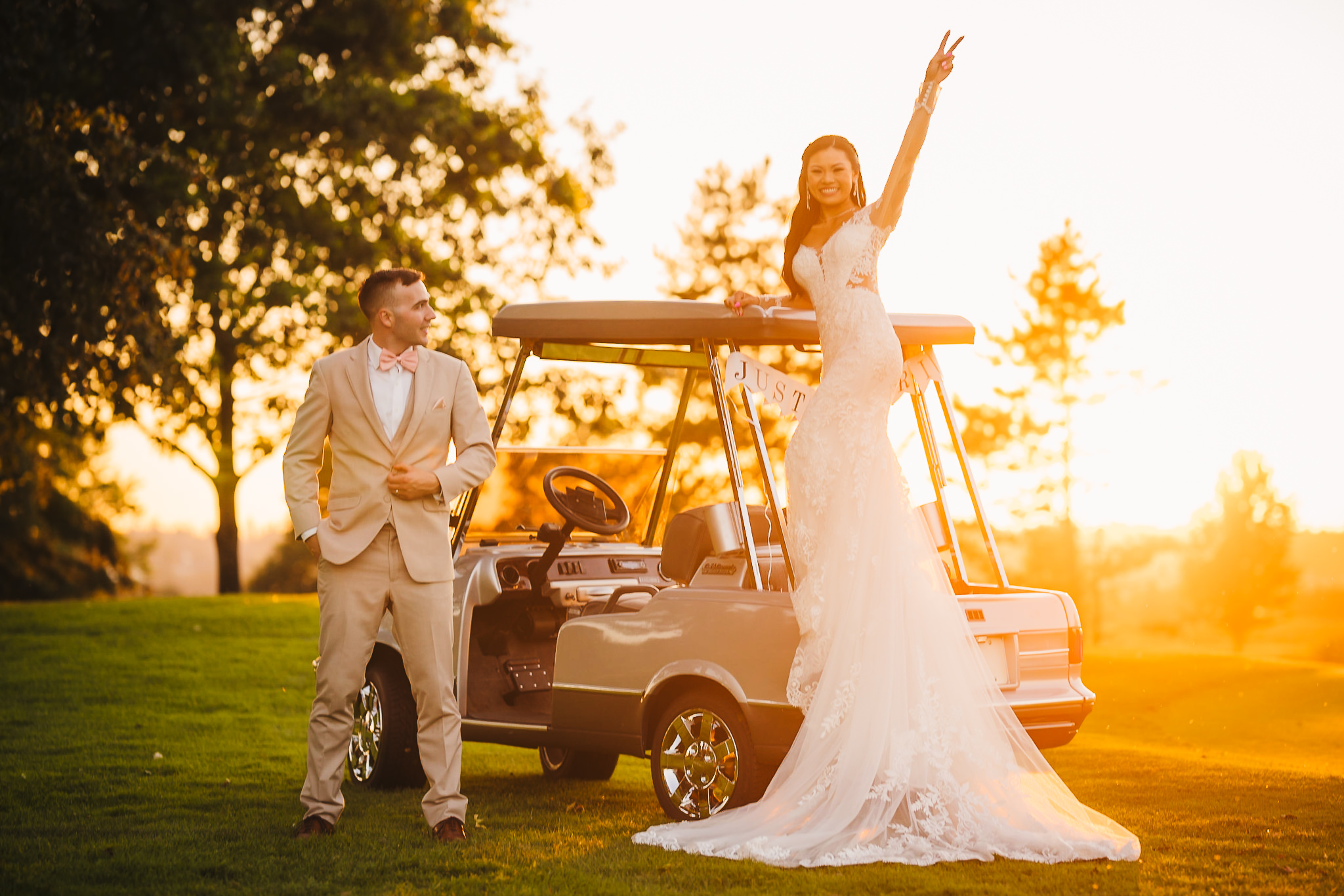 Bride and groom posing with a golf cart