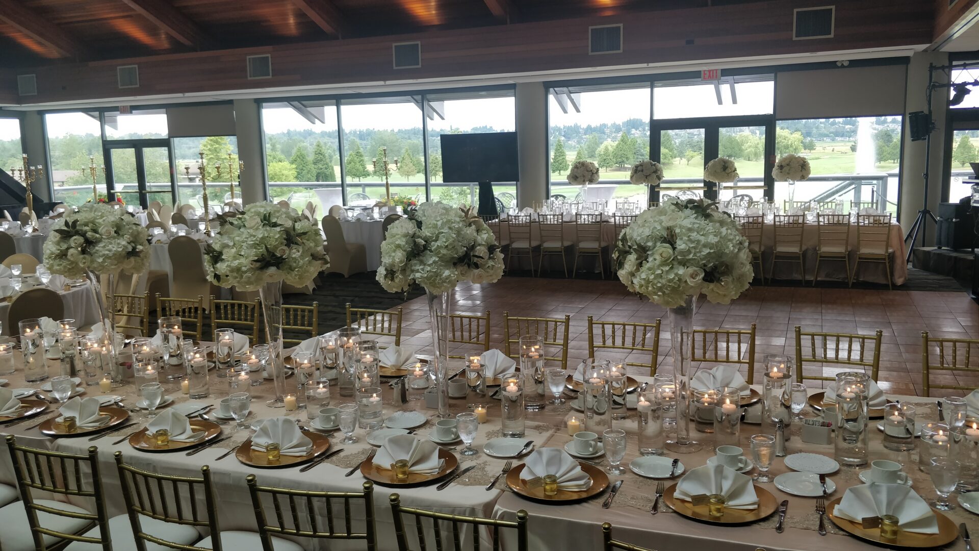 View of tables and chairs set up and decorated in white within the banquet hall