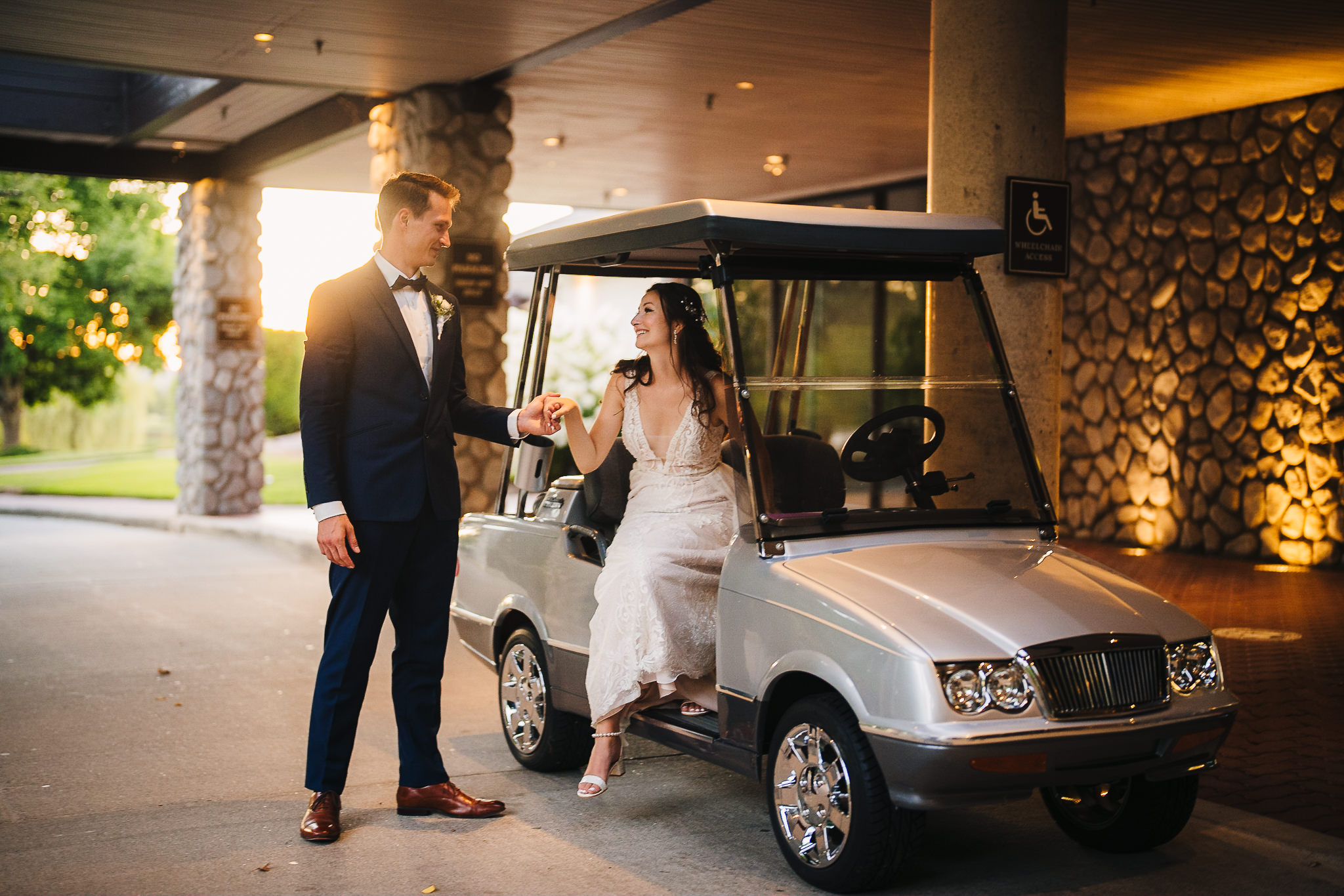Groom offering his hand to the bride as she walks out of a golf cart
