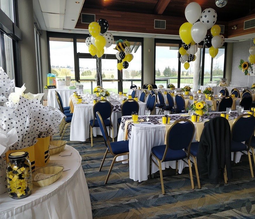 View of tables and chairs decorated in white and blue, along with yellow and dotted balloons